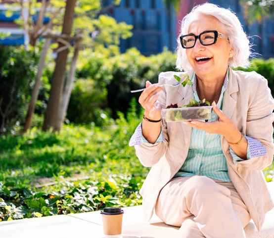 Lady smiles while eating salad