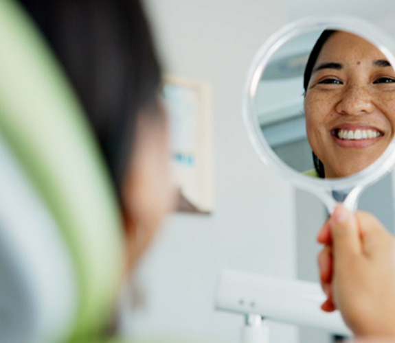 Woman smiling at reflection in dentist office