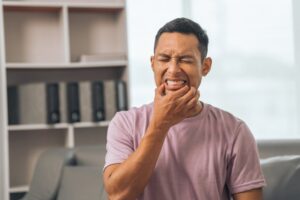 Man holding jaw in pain.