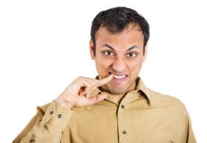Man using finger to get something stuck between his teeth.